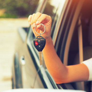 Woman’s hand holding car key. generic first car, young adult car, Millennial.