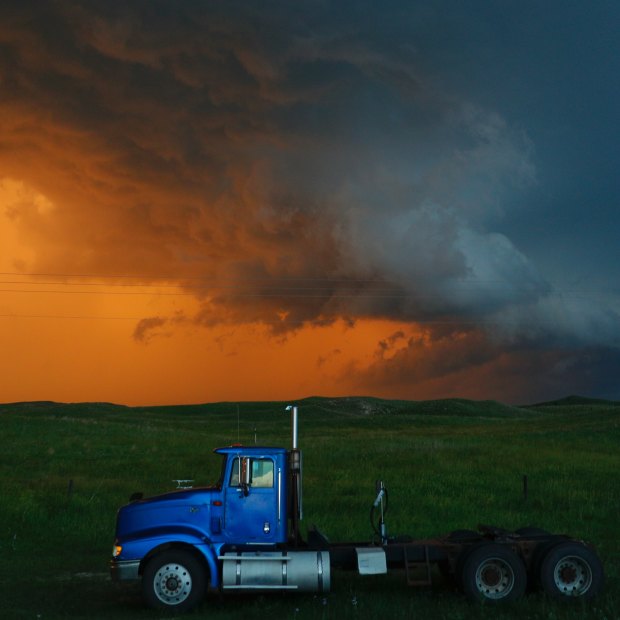 A truck travels on as storms colour the background.