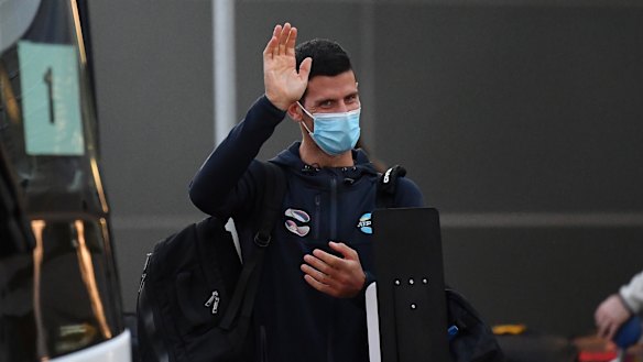 Novak Djokovic waves as he arrives at Adelaide Airport on Thursday. 