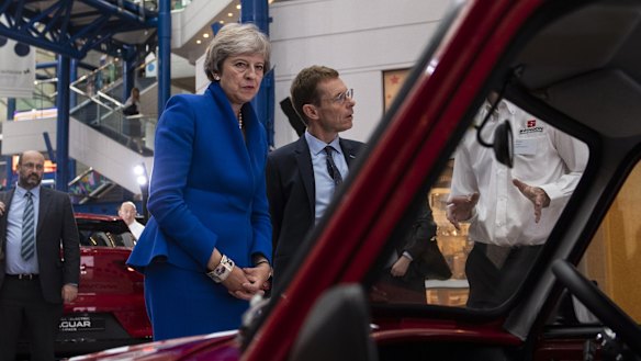 Prime Minister Theresa May inspects an automobile at a summit in Birmingham on Tuesday.