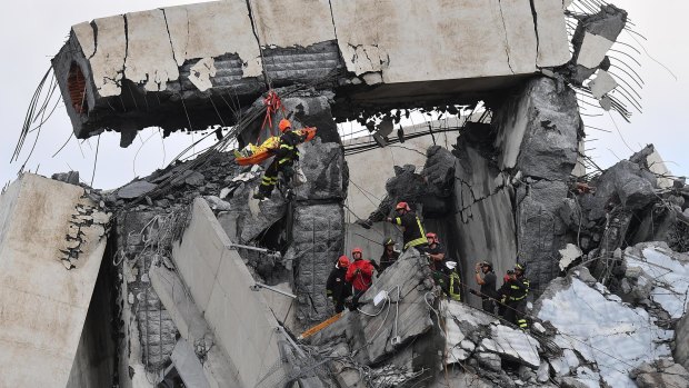Firefighters rescue a person from the rubble of the collapsed Morandi highway bridge in Genoa.