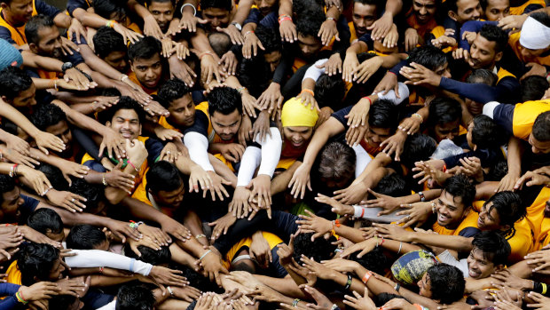 Indian youth prepare to form a human pyramid to break the "Dahi handi," an earthen pot filled with curd hanging above them, as part of the Janmashtami festival in Mumbai, India.