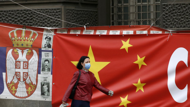 A woman walks by a Chinese flag in Belgrade, Serbia. Chinese envoys have set off diplomatic firestorms with a combative defence whenever their country is accused of not acting quickly enough to stem the spread of the coronavirus pandemic. 
