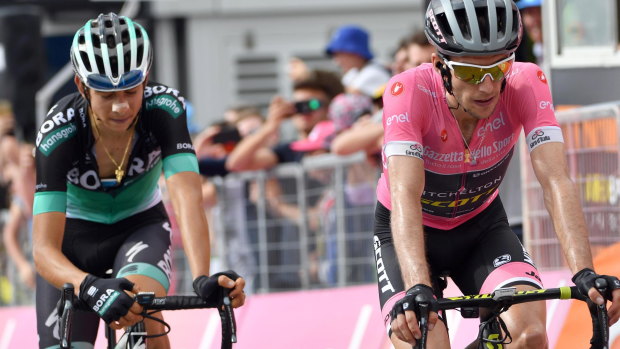 An exhausted Simon Yates, in pink, crosses the finish line after his overall lead was slashed.