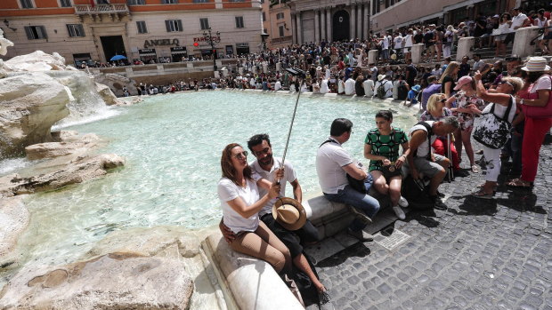 Tourists snap a selfie next to the world-famous Trevi Fountain in Italy.