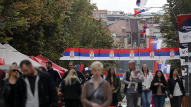 People walk through streets decorated with Serbian flags in northern Kosovo, a Serb-dominated part of ethnically divided town of Mitrovica. 