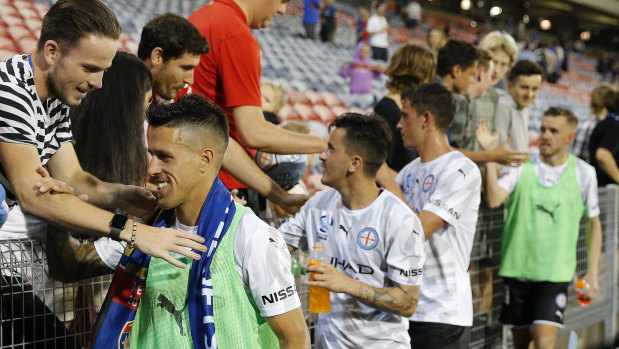 Divided loyalties: A supporter puts a Jets scarf on Melbourne City goalscorer Javier Cabrera (left) after the match against Newcastle.