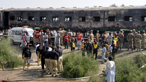 Pakistani soldiers and officials examine the train carriages damaged by fire in Liaquatpur, Pakistan.