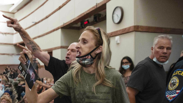 Protesters gesture as they are escorted out of the Clark County School Board meeting at the Clark County Government Centre, in Las Vegas. 