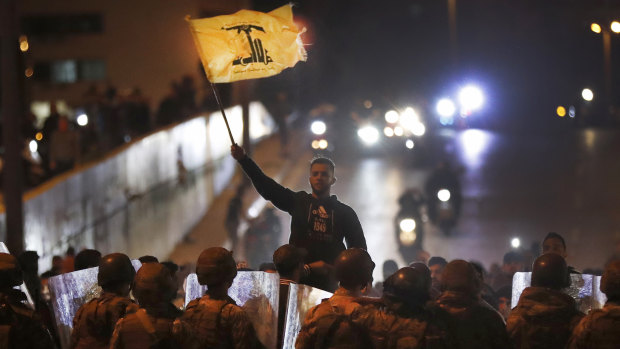 A supporter of the Iran-backed militant Hezbollah group waves his group's flag after a clash erupted between anti-government protesters and the group in Beirut, Lebanon. 