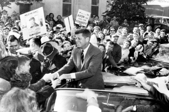 Democratic presidential candidate, Sen. John F. Kennedy shakes hands with supporters along the route of motorcade through suburban Libertyville, Ill. on October 25, 1960.