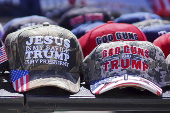 Hats reading, “God, Guns and Trump” and “Jesus is my saviour, Trump is my president” are sold at a campaign rally.