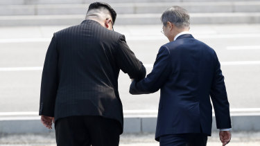 North Korean leader Kim Jong-un leads South Korean President Moon Jae-in across the military demarcation line to the North side of the border.