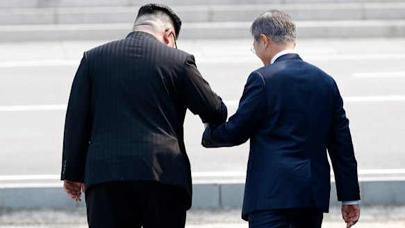 North Korean leader Kim Jong-un leads South Korean President Moon Jae-in across the military demarcation line to the North side of the border.