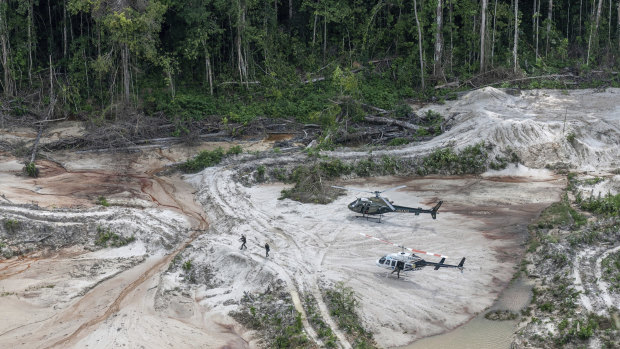 Ibama inspectors walk with their weapons  through an area affected by illegal mining, after landing in Munduruku indigenous lands in Para state in Brazil's Amazon basin. 