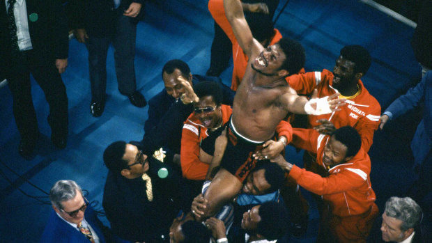 Spinks celebrates as his entourage holds him aloft after his 15-round split decision victory.