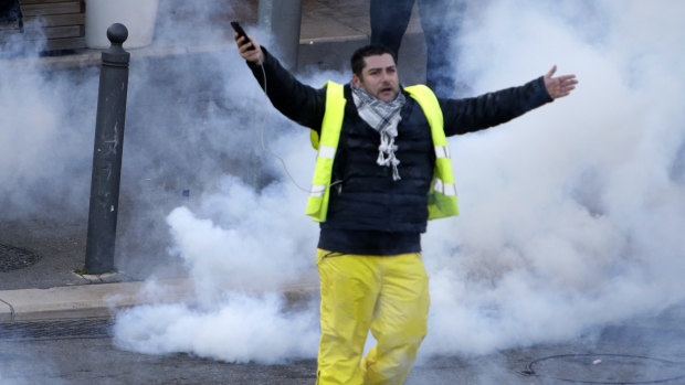 A yellow vest demonstrator gestures through tear gas during a protest on Saturday in Marseille, southern France. 