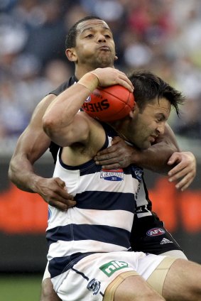 Magpies defender Leon Davis stops Cats midfielder Jimmy Bartel with a strong tackle.