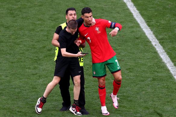Cristiano Ronaldo tries to get away from a pitch invader.