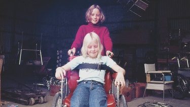 As a child playing in her father’s wheelchair with brother Hugh.