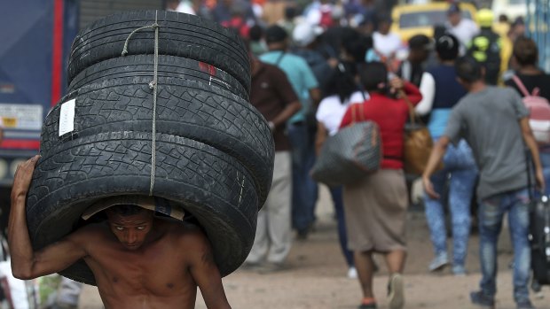 A man carries a set of used tyres into Venezuela through a blind spot on the border near the Simon Bolivar International Bridge in La Parada, Colombia.