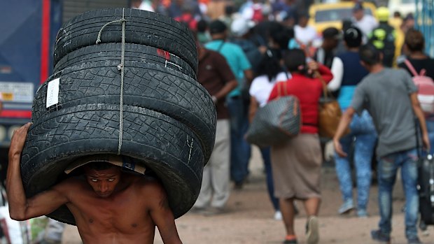 A man carries a set of used tyres into Venezuela through a blind spot on the border near the Simon Bolivar International Bridge in La Parada, Colombia.