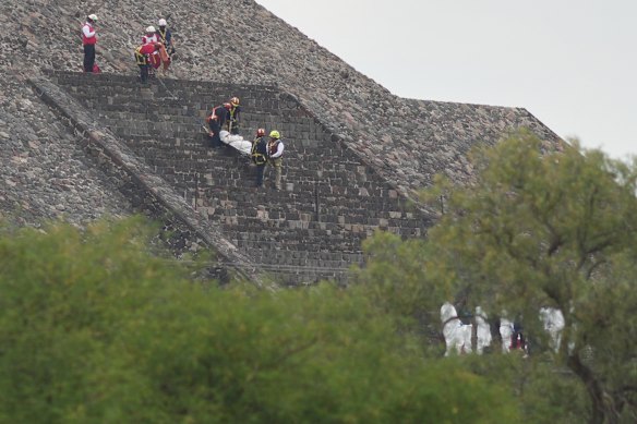 Gli operatori forensi trasportano il corpo di una vittima giù da una piramide dopo che le autorità hanno detto che un uomo armato ha aperto il fuoco, lunedì a Teotihuacan, in Messico.