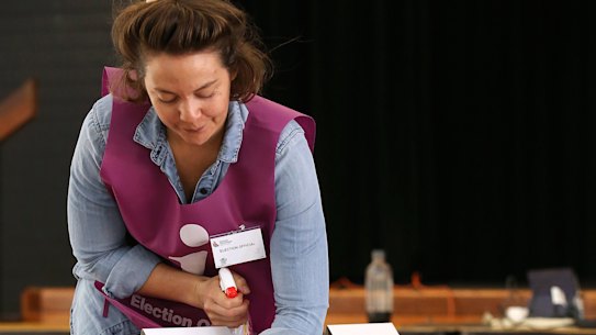 An election official sanitizes voting areas at a polling booth.
