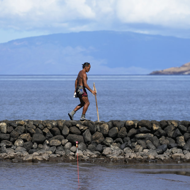 Vicente Ruboi walks along a sea wall in Kihei, Hawaii after the fires destroyed part of Maui.