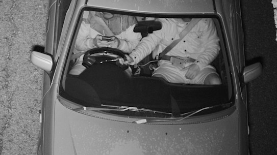 This driver was captured with both hands on a mobile phone while the passenger held the steering wheel.