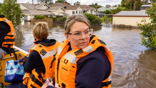 Bailee Harrison, nurse unit manager at Forbes District Hospital, is transported by boat with a crew from Maritime NSW  across flooded streets.