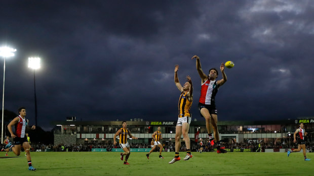 On the ball: Hawthorn's Tom Scully and St Kilda's Hunter Clark under the spotlights at Moorabbin.