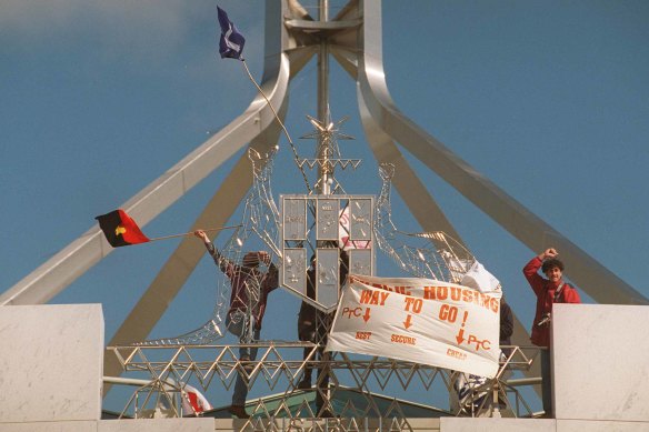 Protestors place flags on the Australian coat-of-arms at the front of Parliament House