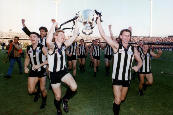 Collingwood players celebrate with the 1990 premiership trophy.