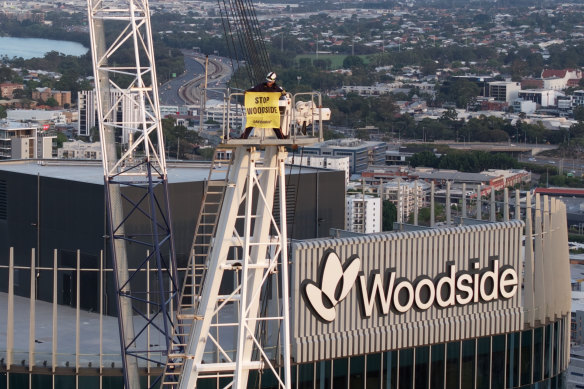 A man stands near the top of the crane holding a banner. 