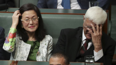 Crossbench MP Bob Katter covers his face while sitting next to Liberal MP Gladys Liu.