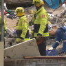 Rescuers go through the debris of the Whalan townhouse that exploded on Saturday. A woman is yet to be located.
