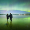 Sky’s the limit: this photo of two people watching the aurora australis light up a southern Tasmanian beach about 5am on Saturday was taken on a digital camera.