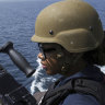 US Navy sailor stands guard next to a machine gun aboard the USS Paul Hamilton in the Strait of Hormuz.