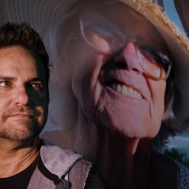 Jason van Genderen stands in front of an image of himself and his mother from the documentary Everybody’s Oma.