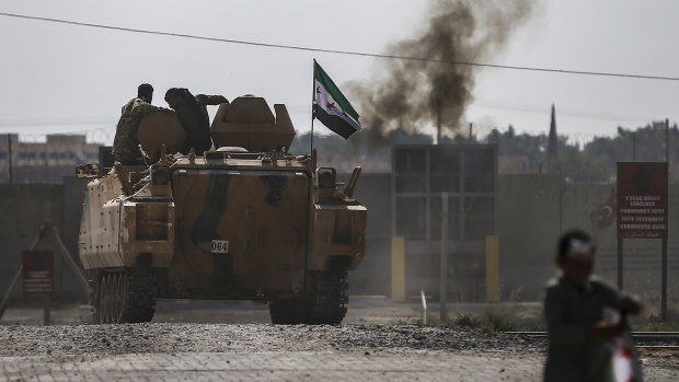 Turkish-backed forces cross the border into Syria onm an armoured personnel carrier.