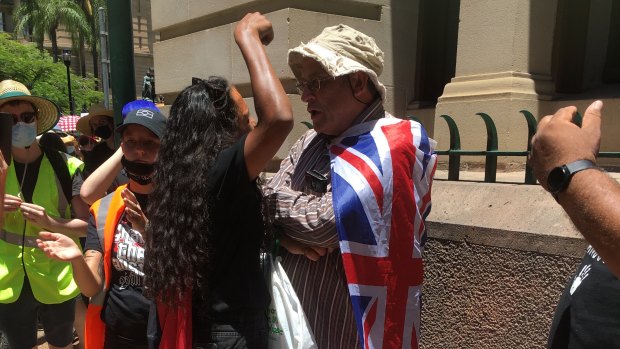 A protester clashes with a member of the public wrapped in an Australian flag at the Invasion Day protest in Brisbane
