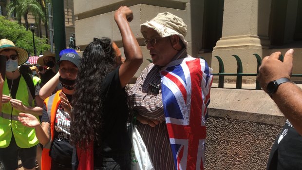 A protester clashes with a member of the public wrapped in an Australian flag at the Invasion Day protest in Brisbane