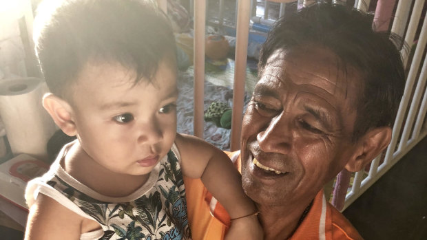 Sudech Paneha with his grandson Tulyawat Prasomkaen, aged one. The extended family lives on the bank of the Tapi River.