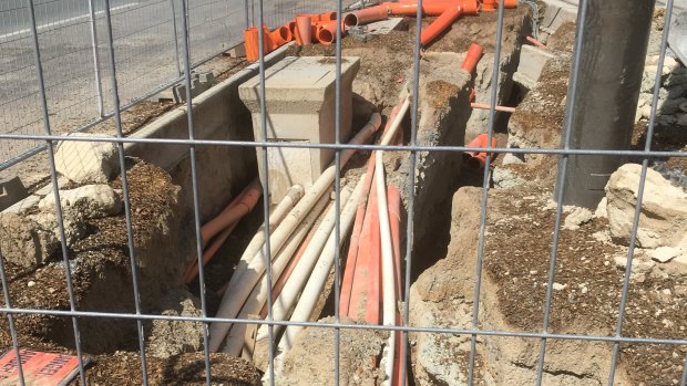 A pit near the intersection of the Federal Highway and Flemington Road in Canberra, where electrical cables appear to be installed just a few millimetres below ground level.