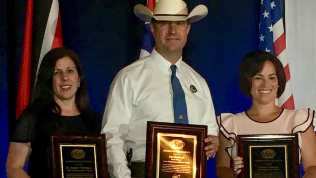 Department of Justice official Angela Williamson receives an award from the International Homicide Investigators Association alongside colleagues James Holland and Christie Palazzolo.