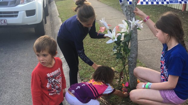Children from the neighbourhood lay flowers outside the Logan house after a woman was found dead.