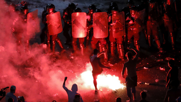 A man kicks a flare at riot police during protests outside the government headquarters, in Bucharest, Romania.