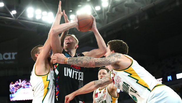 Jack White of United drives to the basket against JackJumpers Jack McVeigh and Josh Adams.