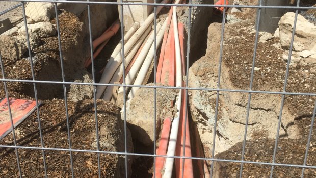 A pit near the intersection of the Federal Highway and Flemington Road in Canberra, where electrical cables appear to be installed just a few millimetres below ground level.